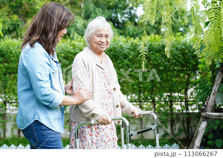 Caregiver help Asian elderly woman disability patient walk with walker in park, medical concept. 113066267