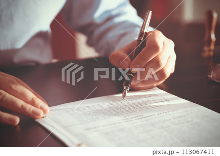 Notary public in office signing document Notary public in office signing document 113067411