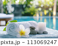 Spa composition with towels and flowers at poolside 113069247