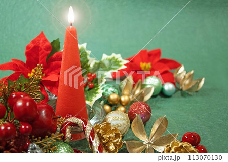 赤いキャンドルに灯る炎とカラフルなクリスマスオーナメント 赤いキャンドルに灯る炎とカラフルなクリスマスオーナメント 113070130