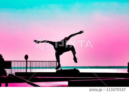 Unrecognizable teenage boy silhouette showing high jump tricks on scooter against Unrecognizable teenage boy silhouette showing high jump tricks on scooter against 113070587