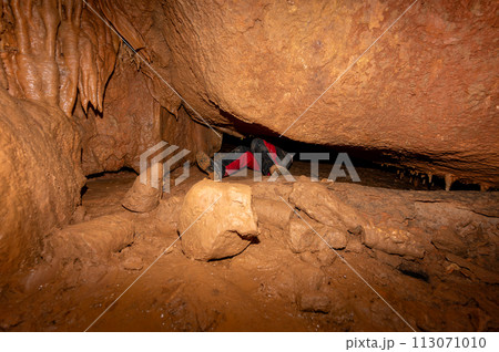 A speleologist with helmet and headlamp exploring a cave with rich stalactite and stalagmite A speleologist with helmet and headlamp exploring a cave with rich stalactite and stalagmite 113071010