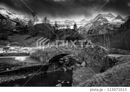 Sunset over the Pyrenees mountains, Circus of Gavarnie and the old stone bridge spanning the stream  113071013