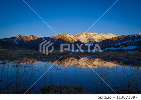 Sunset over the Pyrenees mountains with the reflection of the peaks in the water of the lake 113071097