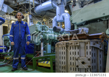 Marine Engineer in blue overall working in Engine room of ship. Work at sea. Motorman. Marine Engineer in blue overall working in Engine room of ship. Work at sea. Motorman. 113071131