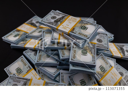 Stacks of money packed by a bank lie in a heap on a black background. One hundred dollar bills wrapped in bank tape lie on a black isolated background. Stacks of money packed by a bank lie in a heap on a black background. One hundred dollar bills wrapped in bank tape lie on a black isolated background. 113071355
