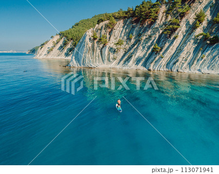 Paddle boarding in Mediterranean sea with mountain coastline. Aerial drone view 113071941