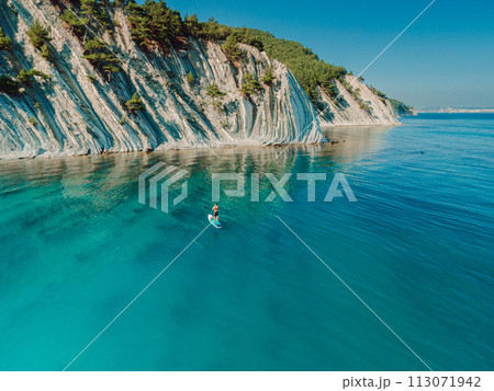 Man on stand up paddle board in Mediterranean sea with scenic landscape. 113071942