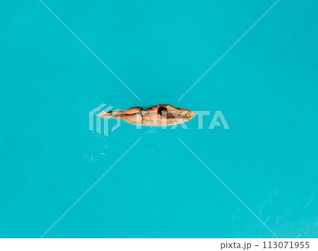 Surf girl relaxing on surfboard in ocean. Aerial view of woman during surfing 113071955
