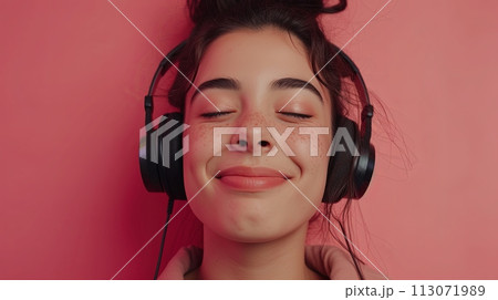 Young happy woman in headphones listen to music with closed eyes have fun isolated on plain pink background. People lifestyle concept 113071989
