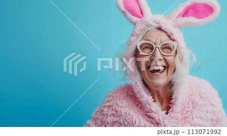 stylish Senior woman in Easter bunny costume smiling positive emotions blue background with place for text 113071992