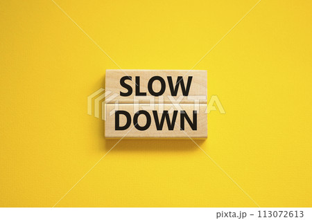 Time to slow down symbol. Concept words Slow down on wooden blocks on a beautiful yellow background. Business and slow down concept. Copy space. 113072613