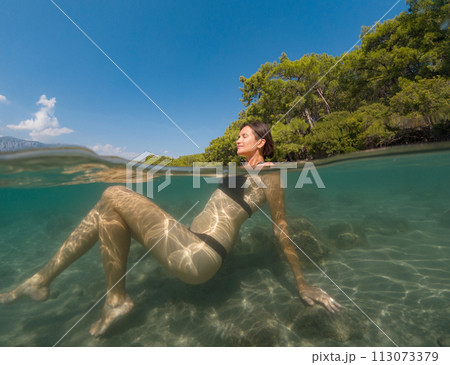 Young female on holidays enjoy floating on a crystal clear water beach of Antalya Turkey. Asian beautiful woman swimming with open arms. Relax and tranquility. Travel and Holiday concept. Young female on holidays enjoy floating on a crystal clear water beach of Antalya Turkey. Asian beautiful woman swimming with open arms. Relax and tranquility. Travel and Holiday concept. 113073379