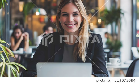 Smiling businesswoman at a cafe with her laptop. Casual professional working remotely. Modern freelancing lifestyle. Entrepreneurial spirit captured. AI 113073694