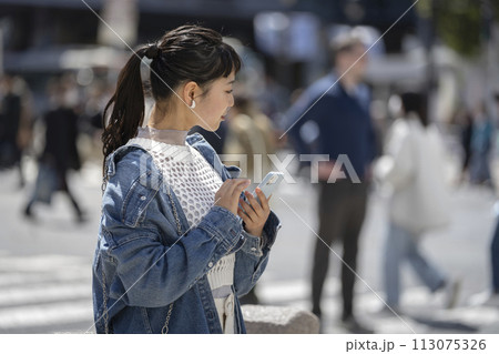 街角に立つスマートフォンを持った若い女性　横顔 113075326