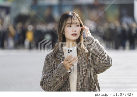 街角に立つスマートフォンを持った若い女性　 113075427