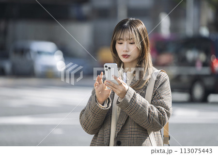 街中でスマートフォンを操作する20代の女性 街中でスマートフォンを操作する20代の女性 113075443