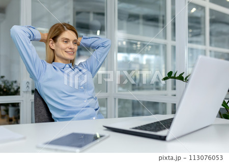 A professional woman takes a moment to relax in her bright office, exuding calmness and confidence behind her laptop. A professional woman takes a moment to relax in her bright office, exuding calmness and confidence behind her laptop. 113076053