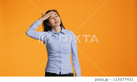 Filipino female model dealing with painful headache on camera, rubbing temples to ease pressure. Young sick person suffering from migraine in studio, being unwell and under stress. Filipino female model dealing with painful headache on camera, rubbing temples to ease pressure. Young sick person suffering from migraine in studio, being unwell and under stress. 113077431
