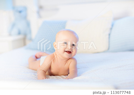 Baby boy on white bed 113077748