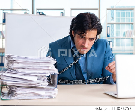 Chained male employee unhappy with excessive work 113078752