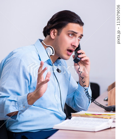 Call center operator working at his desk 113079036
