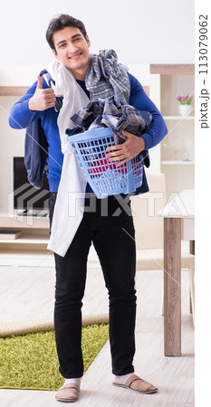 Young man collecting dirty clothing for laundry Young man collecting dirty clothing for laundry 113079062
