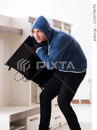 Man burglar stealing tv set from house Man burglar stealing tv set from house 113079078