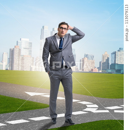 Young businessman at crossroads in uncertainty concept 113079113
