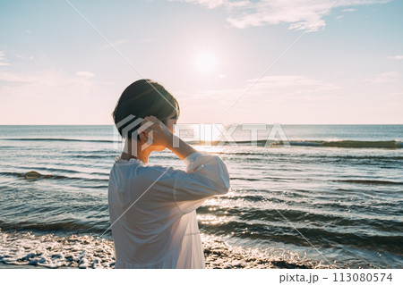 海に沈む太陽と女性のシルエット 113080574