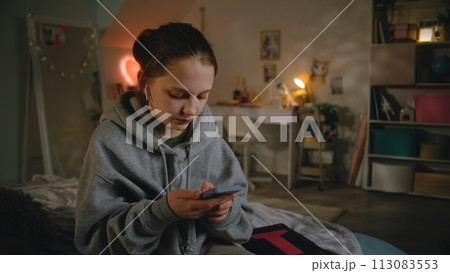 Young girl in headphones uses smartphone, then talks with friend 113083553