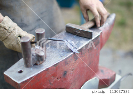 Forging iron. Working hands with a hammer forge iron 113087582