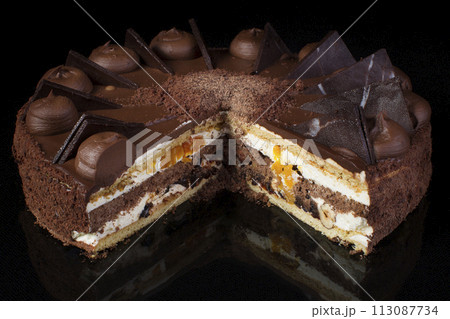 A piece of chocolate cake with white cream on a black background A piece of chocolate cake with white cream on a black background 113087734