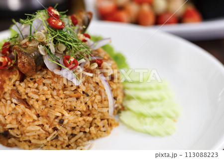 Thai food, Fried jasmine rice with canned fish mackerel in tomato sauce, topped with red chili, red onion, lettuce and kaffir lime leaves. 113088223