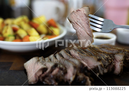 Close-up of female hand holds Pieces of roasted meat. Woman hand holding with grilled beef steak. Concept of eating out. Close-up of female hand holds Pieces of roasted meat. Woman hand holding with grilled beef steak. Concept of eating out. 113088225