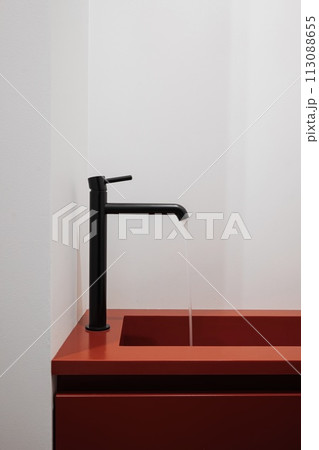 Red countertop with black faucet on a bathroom sink 113088655