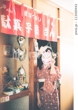 駄菓子屋の前にいるお面をつけた浴衣の女の子 113089442