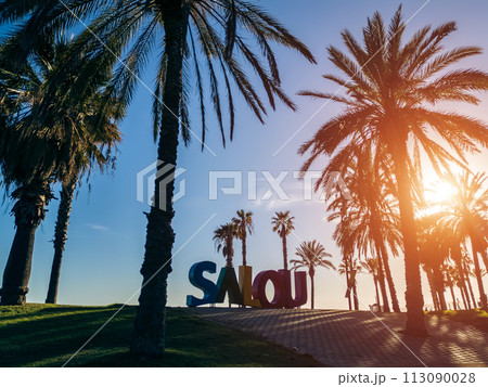 colorful letters of Salou town, palm trees andl beach at sunset, Catalonia, Spain colorful letters of Salou town, palm trees andl beach at sunset, Catalonia, Spain 113090028