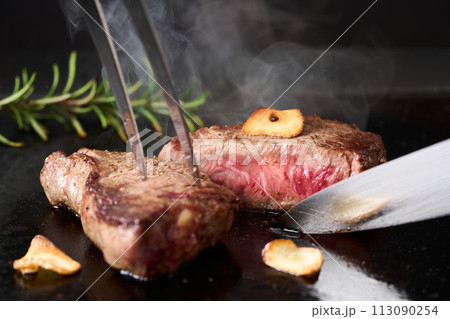 牛もも肉のステーキをカットする 113090254