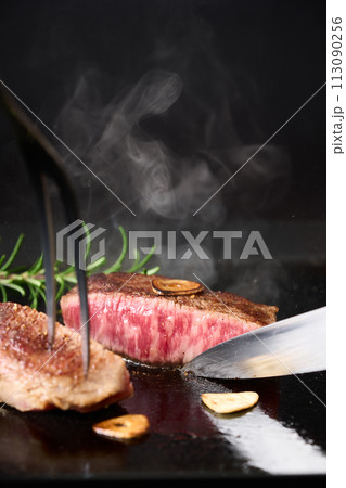 牛もも肉のステーキをカットする 113090256