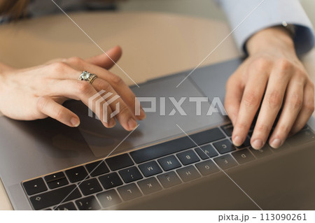 Hands of an executive woman dressed formally in a light blue shirt typing on her laptop 113090261