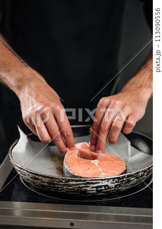 Man cooking salmon steak roasting on parchment Man cooking salmon steak roasting on parchment 113090556