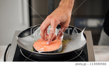 Man cooking salmon steak roasting on parchment Man cooking salmon steak roasting on parchment 113090560