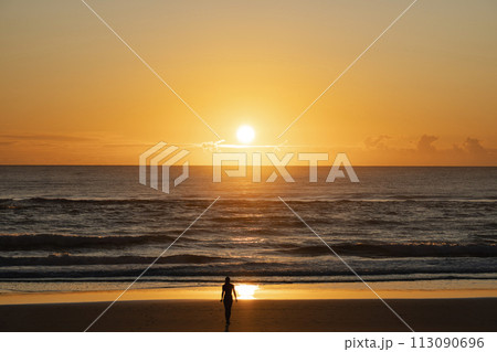 Silhouette of an isolated confident woman on the seashore during sunset Silhouette of an isolated confident woman on the seashore during sunset 113090696