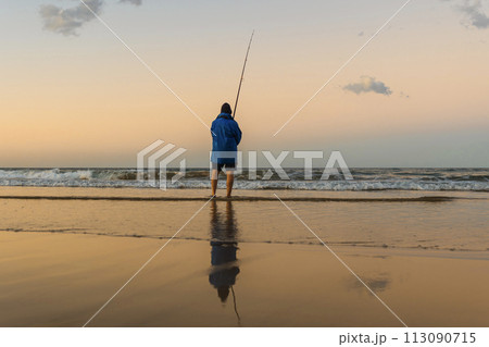 Fisherman fishing on the shore of a Pacific beach during the last hours of the day. Copy space Fisherman fishing on the shore of a Pacific beach during the last hours of the day. Copy space 113090715