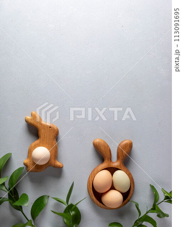 Organic Easter eggs in wooden figures plates as bunny and carrot, green twigs on gray. Copy space. Organic Easter eggs in wooden figures plates as bunny and carrot, green twigs on gray. Copy space. 113091695