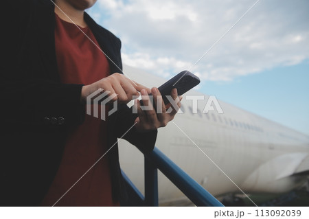 Young asian woman in international airport, using mobile smartphone and checking flight at the flight information board 113092039