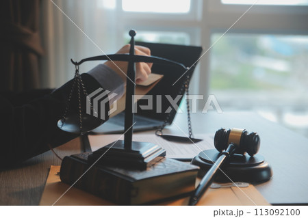 Business and lawyers discussing contract papers with brass scale on desk in office. Law, legal services, advice, justice and law concept picture with film grain effect Business and lawyers discussing contract papers with brass scale on desk in office. Law, legal services, advice, justice and law concept picture with film grain effect 113092100