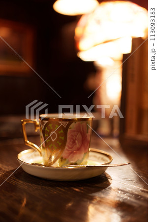 カウンターでスタンドライトに照らされるコーヒーカップ 113093183
