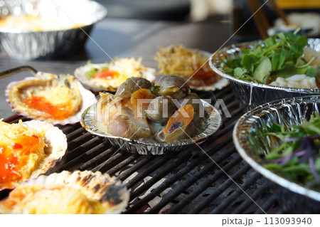 various types of clams are grilled on a grill and then dipped in seasoning and eaten. 113093940